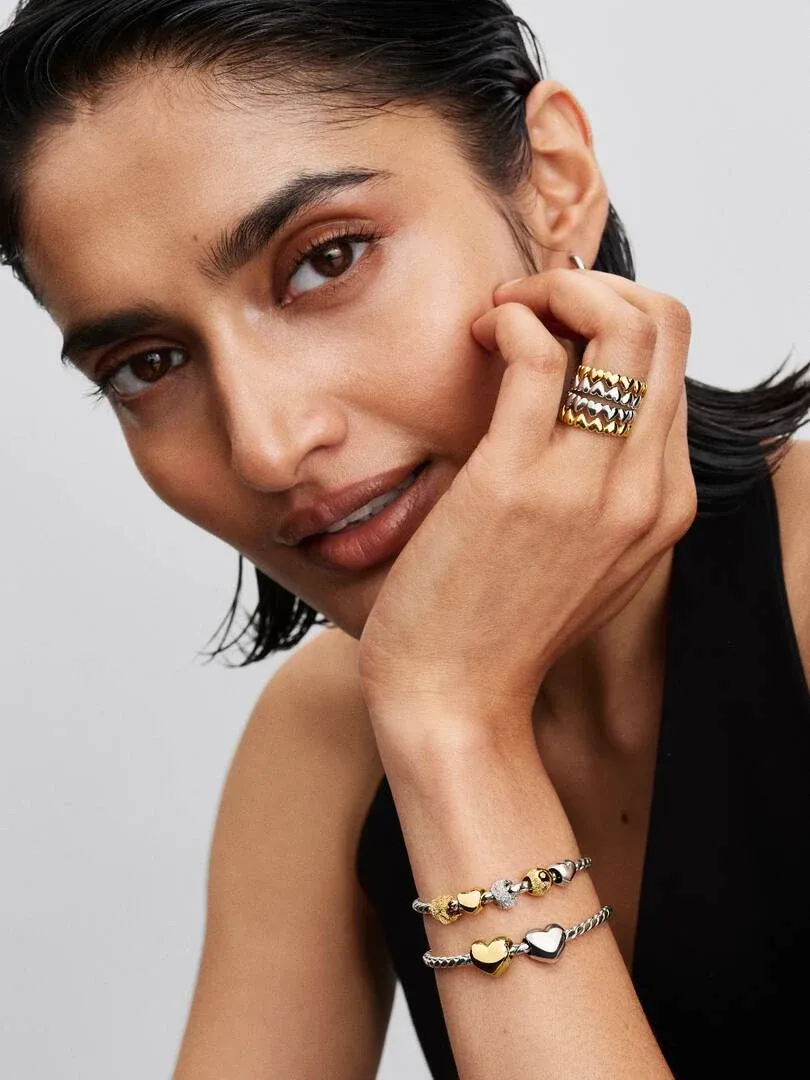 Close-up of a model wearing heart charm bracelets, side view focused on the wrist.