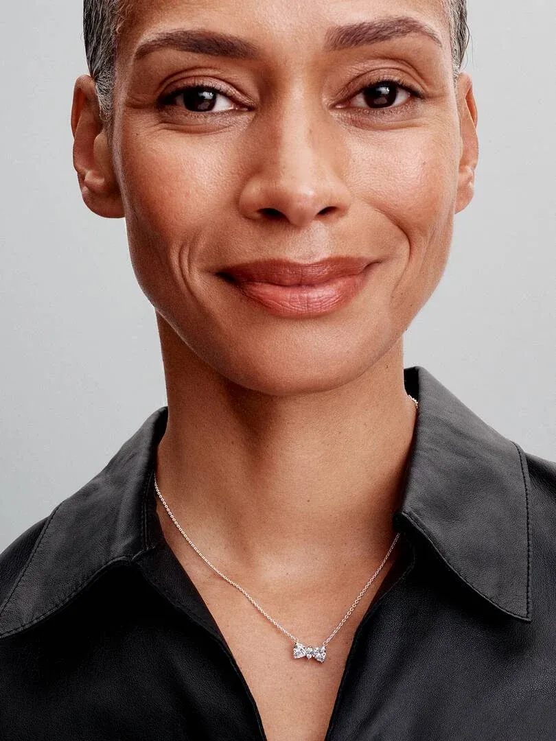 Close-up of the bow necklace on a model's neck, front view against a neutral background.