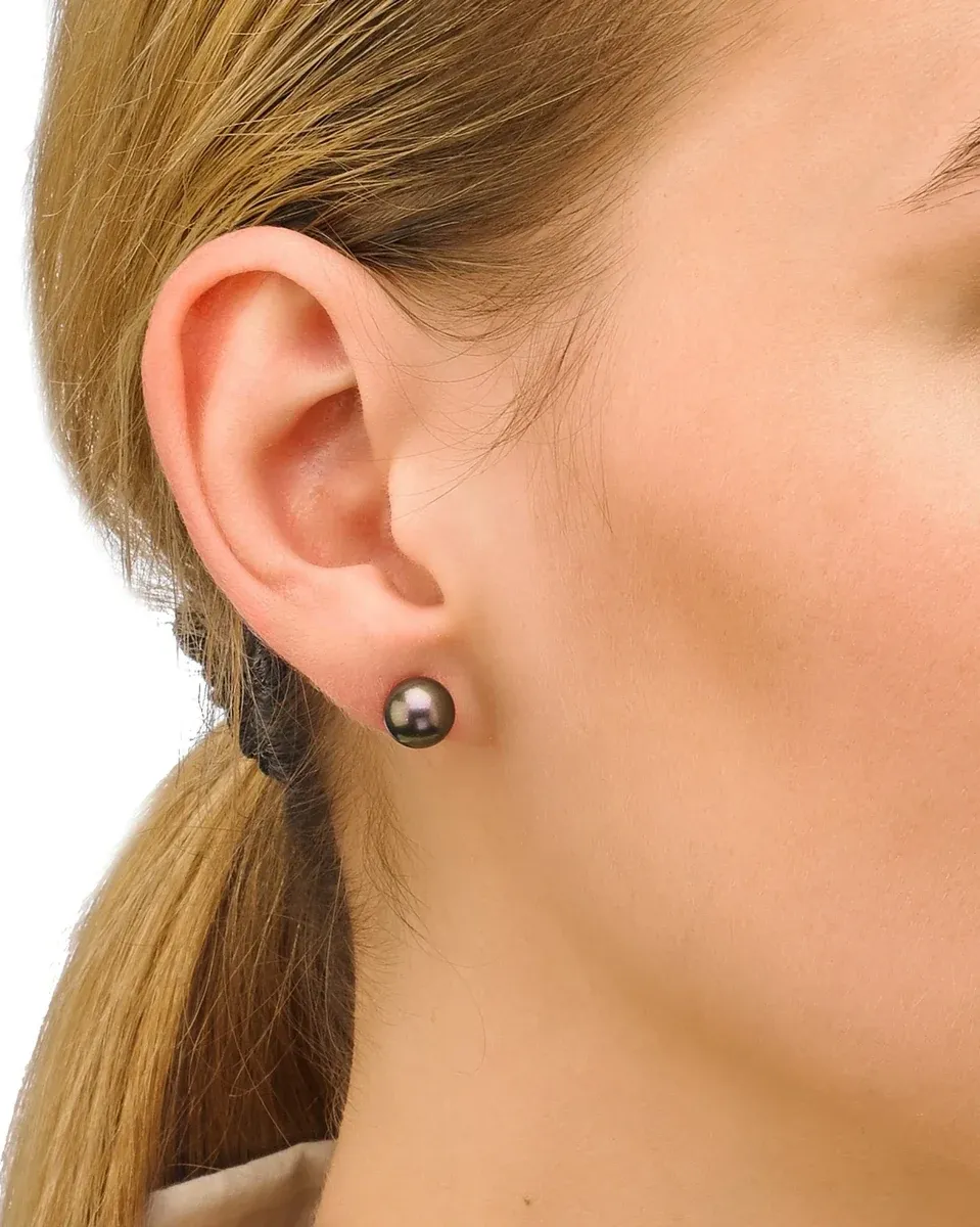 Gros plan latéral d'une boucle d'oreille perle noire portée sur le lobe de l'oreille, fond neutre flou.