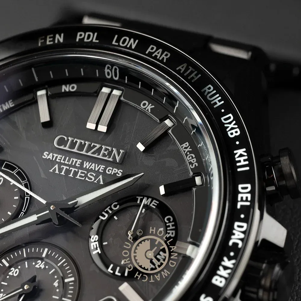 Close-up of the textured dial and bezel with city codes, blurred dark background.