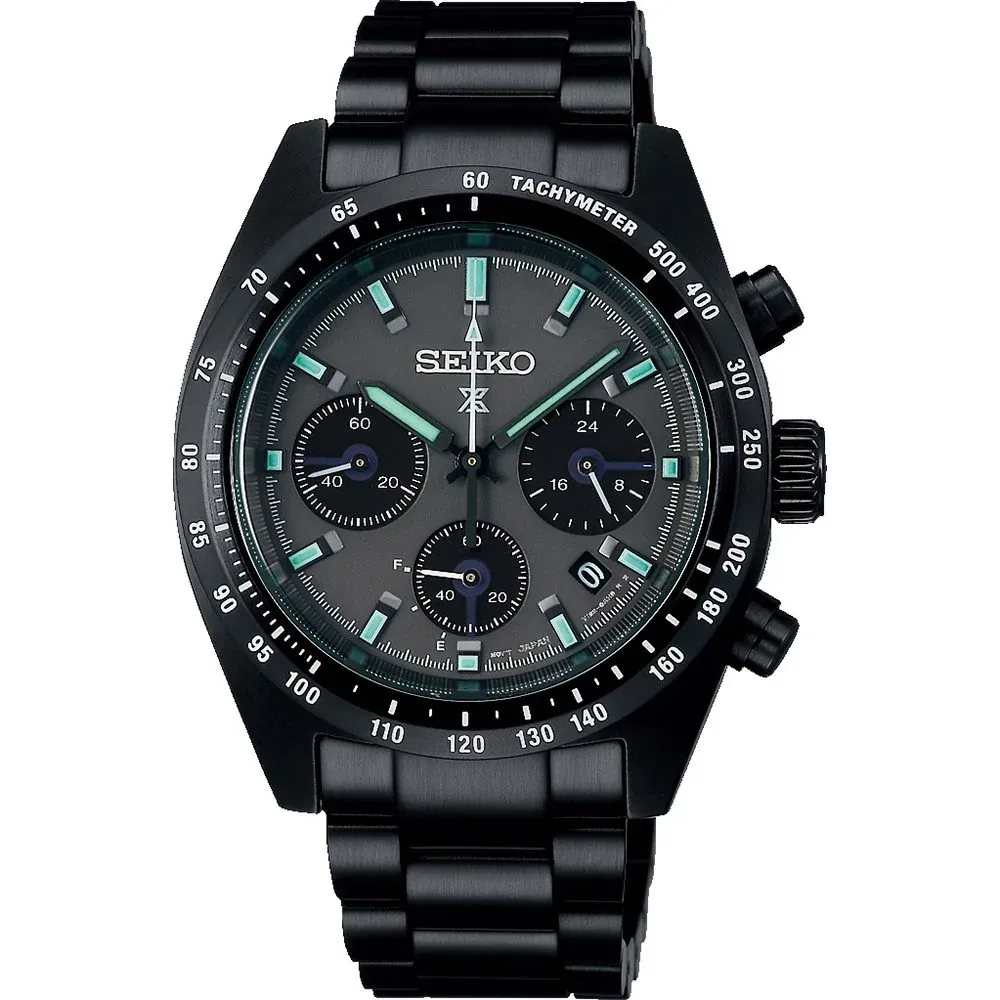 Vista frontal del reloj con esfera negra y bisel taquimétrico, centrado sobre fondo blanco.