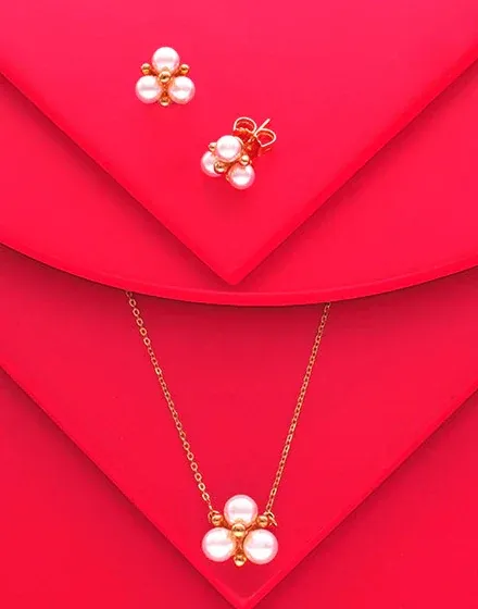 Collar y pendientes de perlas sobre superficie roja curva, toma cenital con composición geométrica.