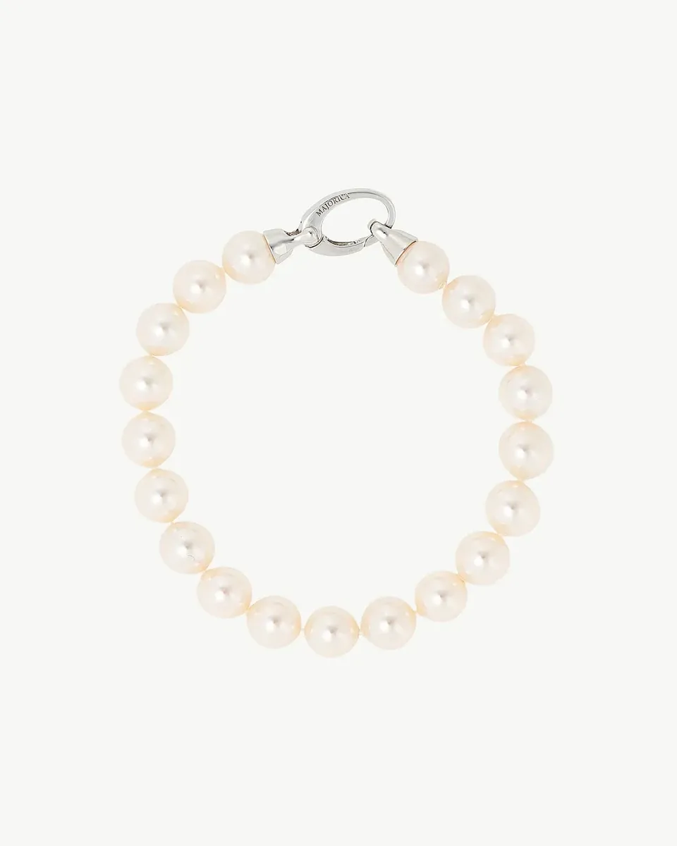 White pearl bracelet arranged in a circle on a white background, top view showing the silver clasp detail.
