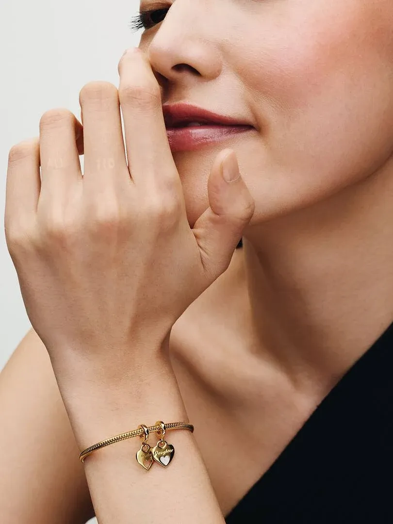 Close-up van de pols met de dubbele hart charm, zijaanzicht tegen een neutrale achtergrond.