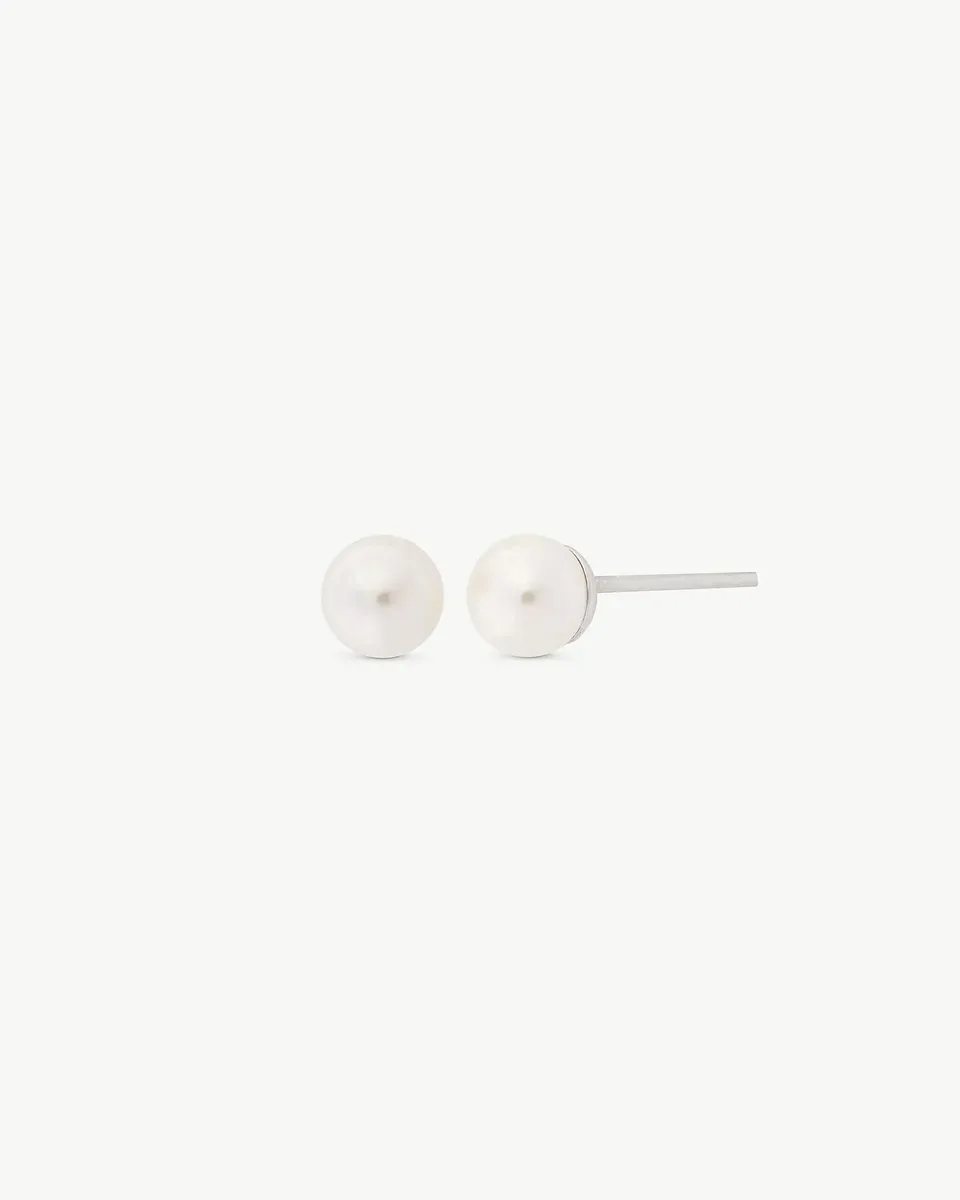 Pendientes de perla blanca sobre fondo blanco, vista frontal y lateral con detalle del cierre de pincho.