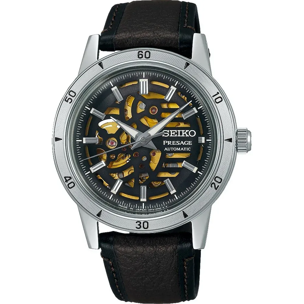Vista frontal del reloj con esfera esqueleto y correa de cuero marrón sobre fondo blanco