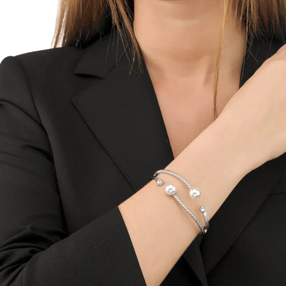 Brazalete puesto en muñeca femenina, modelo con blazer negro, fondo neutro