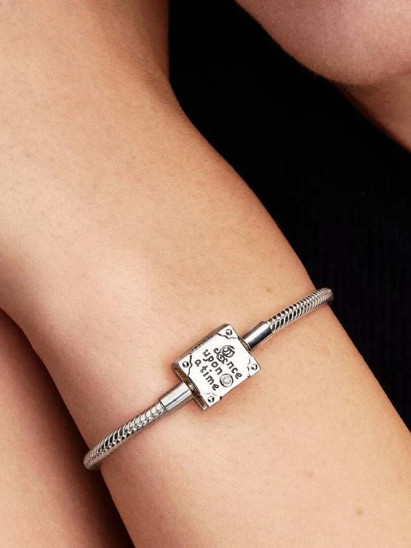 Close-up van de armband met boeksluiting om een pols, zijaanzicht tegen een donkere achtergrond.