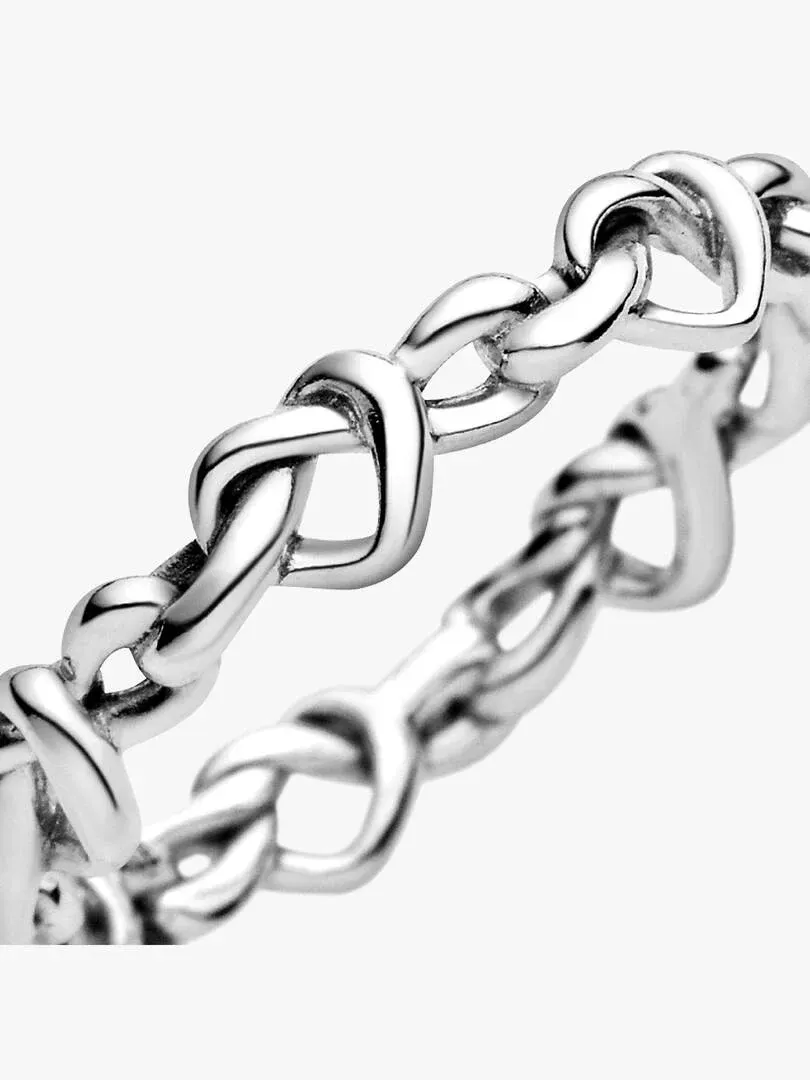 Makro-Nahaufnahme des ineinander verschlungenen Herzmusters aus Silber, Seitenansicht auf weißem Hintergrund.