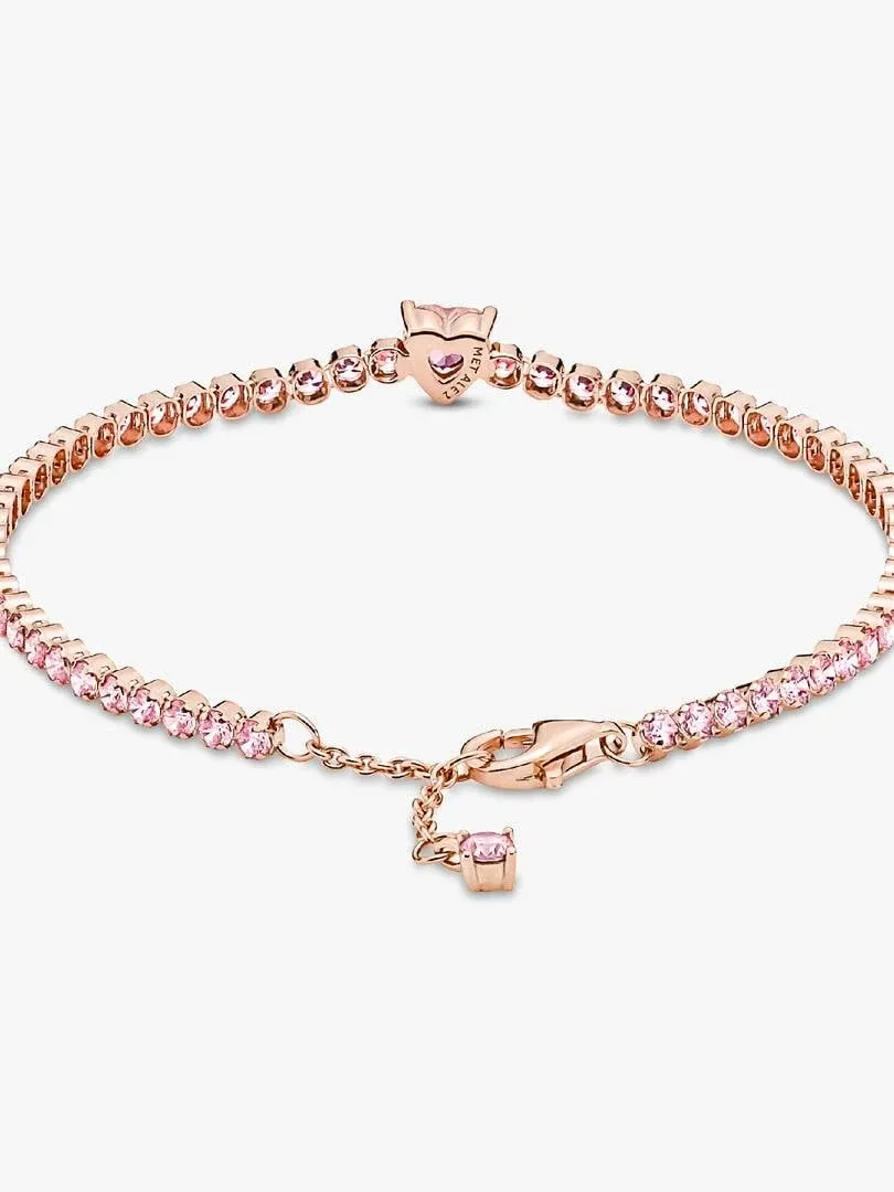 High-angle view of the tennis bracelet on a white background, showing the clasp and heart-shaped center stone.