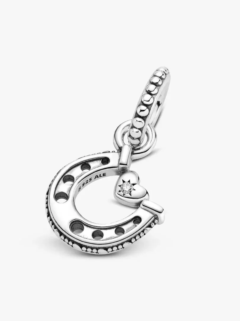 Silver horseshoe charm shown at a diagonal profile angle, white background, focus on engraving and center stone.