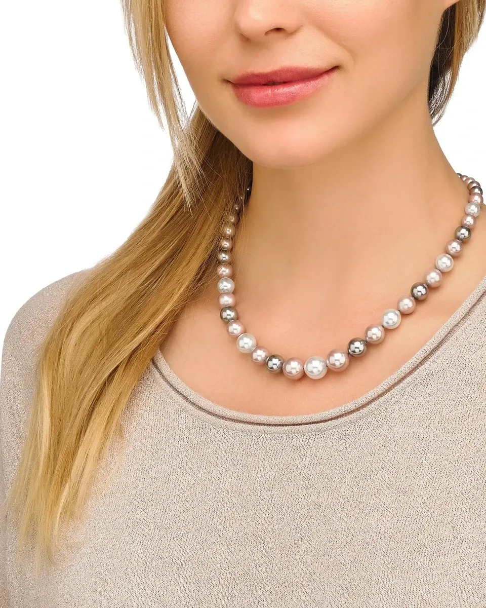 Primer plano del collar de perlas puesto en el cuello de una modelo, fondo neutro y prenda en tono beige.