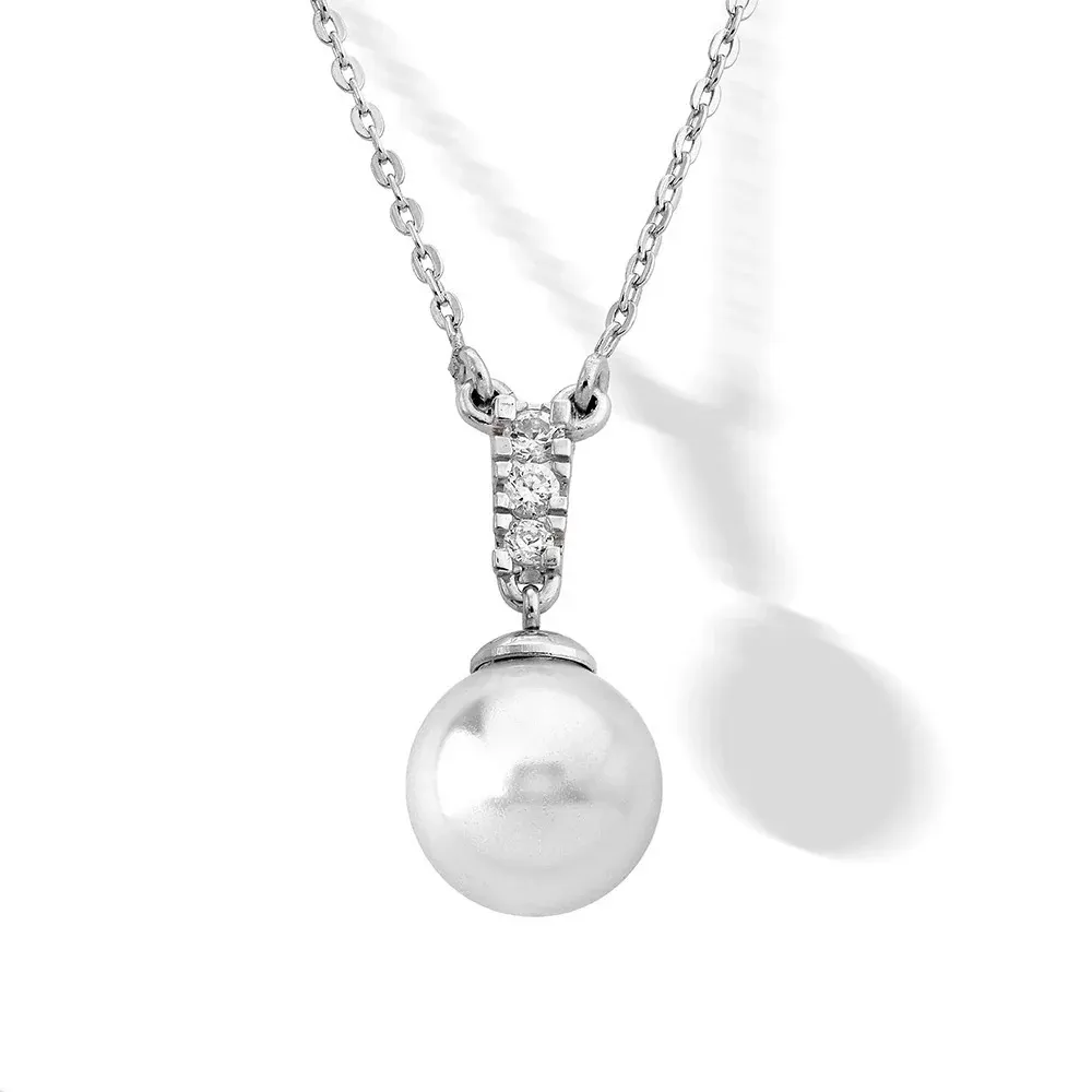 Primer plano frontal de colgante con perla blanca y circonitas sobre cadena de plata, fondo blanco.