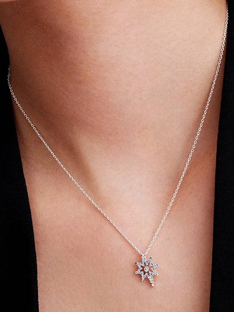 Close-up of the star pendant on a model's neck, front view with dark background.
