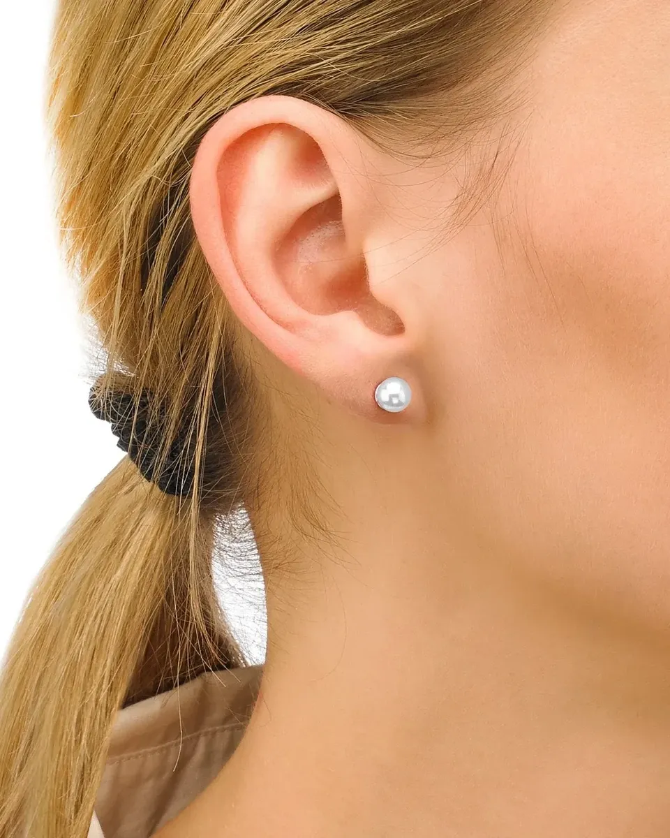 Boucle d'oreille en perle blanche portée au lobe de l'oreille, vue de profil sur fond blanc