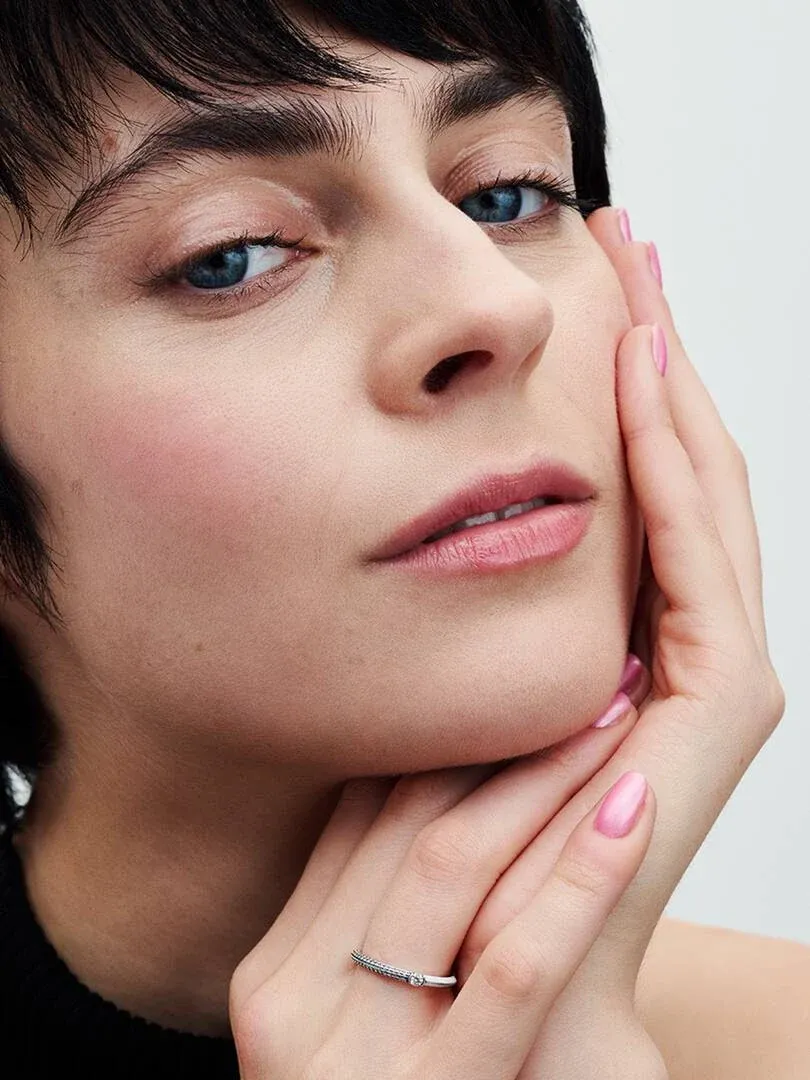 Gros plan d'un modèle portant la bague au doigt, vue de profil centrée sur la main et le visage.