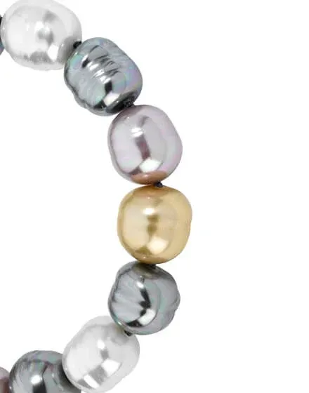 Primer plano de perlas barrocas multicolor en curva, fondo blanco, enfoque en texturas y reflejos.