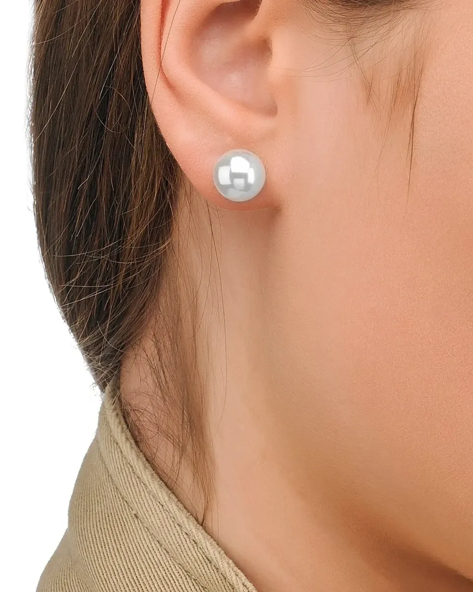 Boucle d'oreille en perle blanche portée au lobe de l'oreille, gros plan latéral, fond neutre.