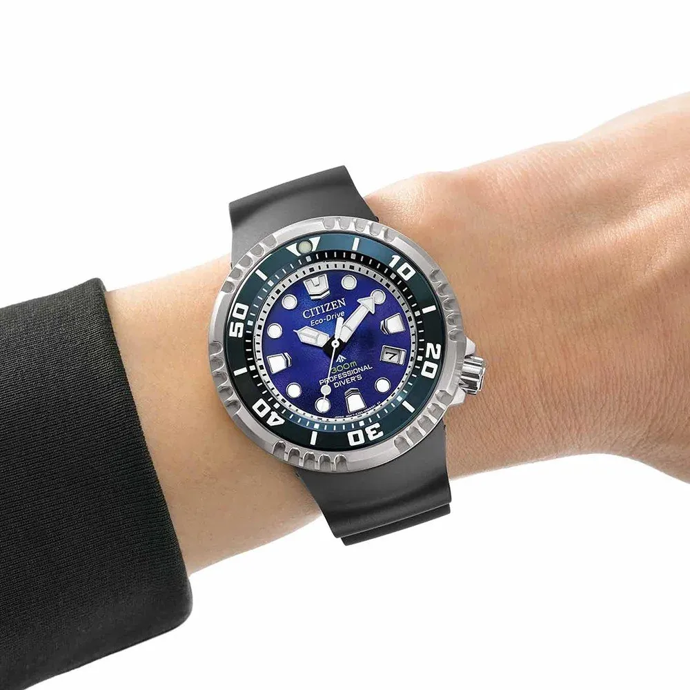 Reloj puesto en muñeca con manga negra, fondo blanco, primer plano en ángulo