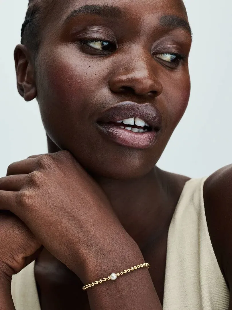 Gros plan du bracelet au poignet, vue de profil avec modèle sur fond neutre.