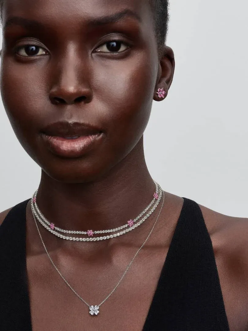 Nahaufnahme eines Models mit rosa Ohrsteckern und einer zweireihigen Edelsteinkette.