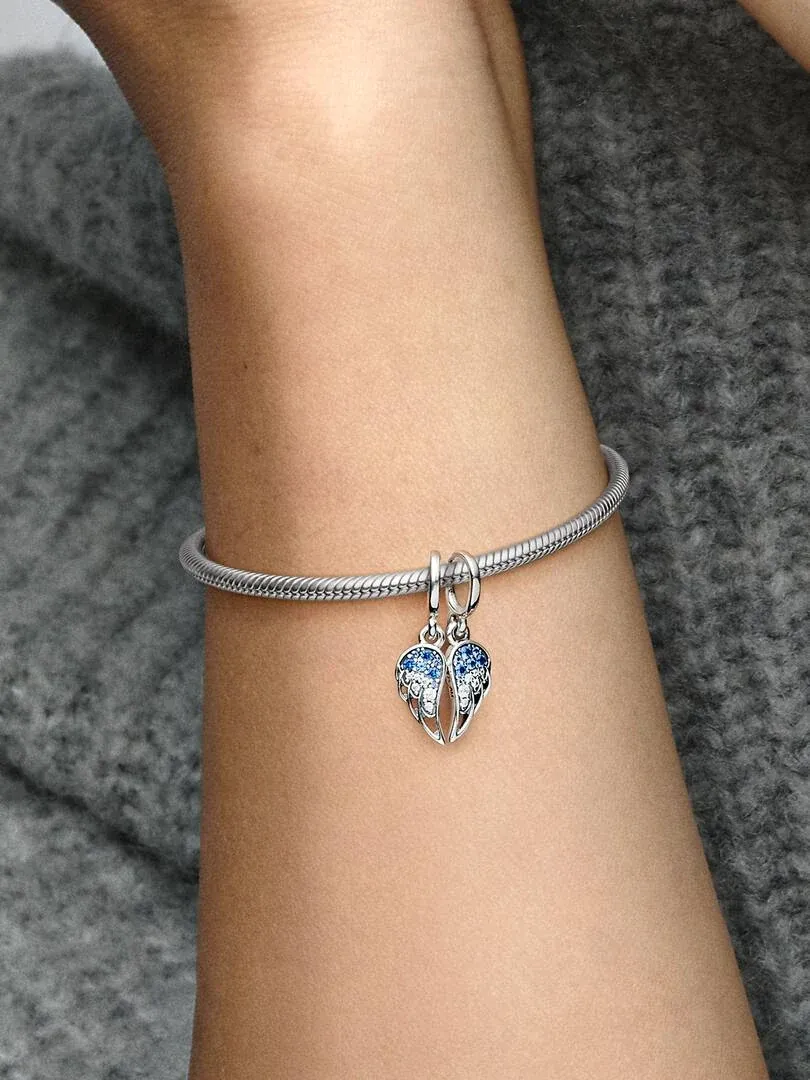 Charm de alas con cristales azules en una pulsera de plata, toma lateral sobre la muñeca.