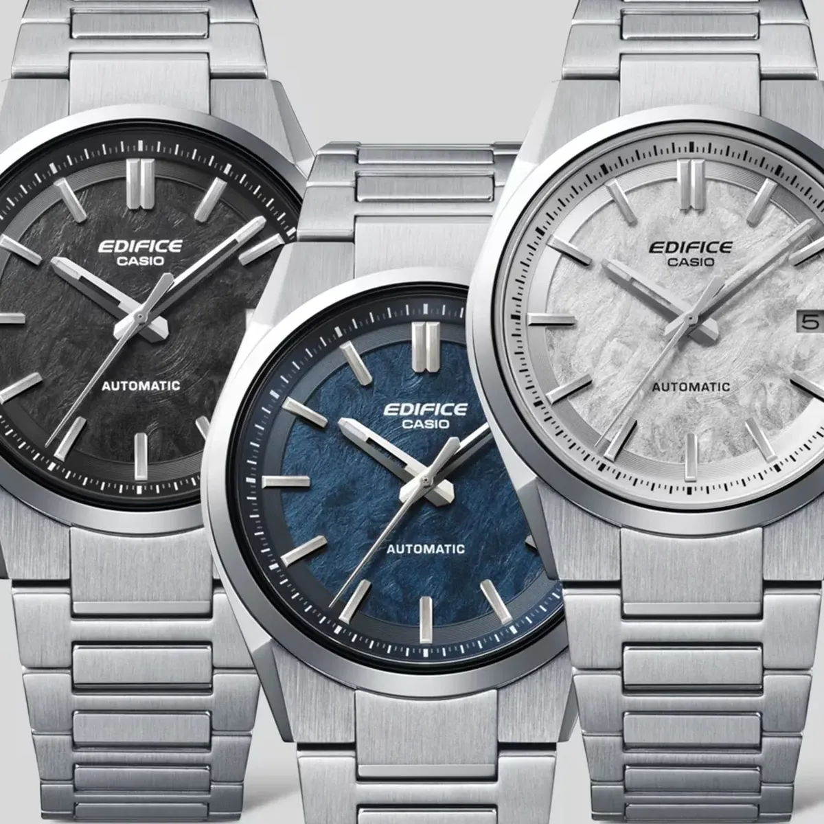 Tres relojes con esferas en color negro, azul y blanco, dispuestos en primer plano sobre fondo neutro.
