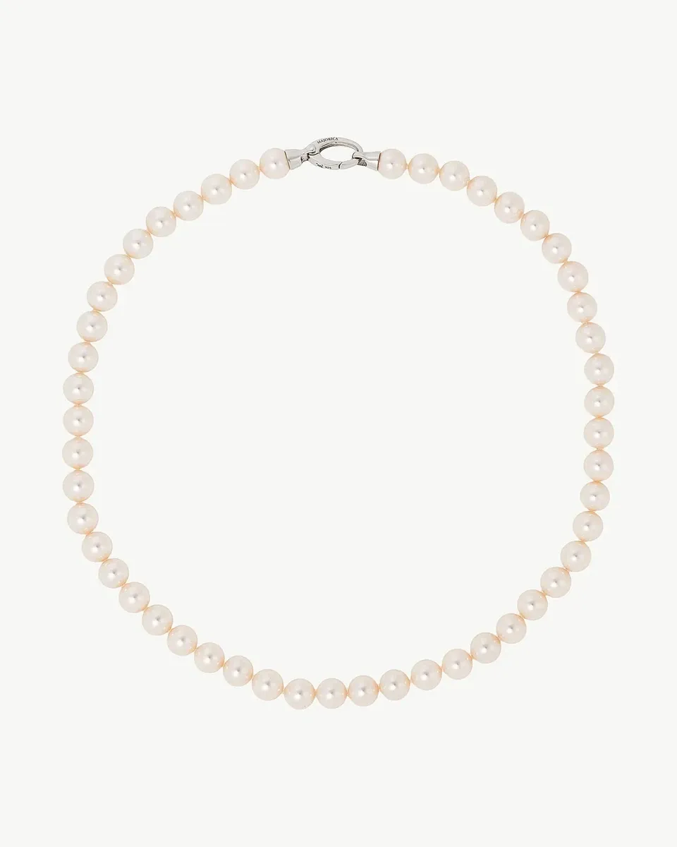 Pearl necklace arranged in a circle on a white background, top view showing the clasp detail.