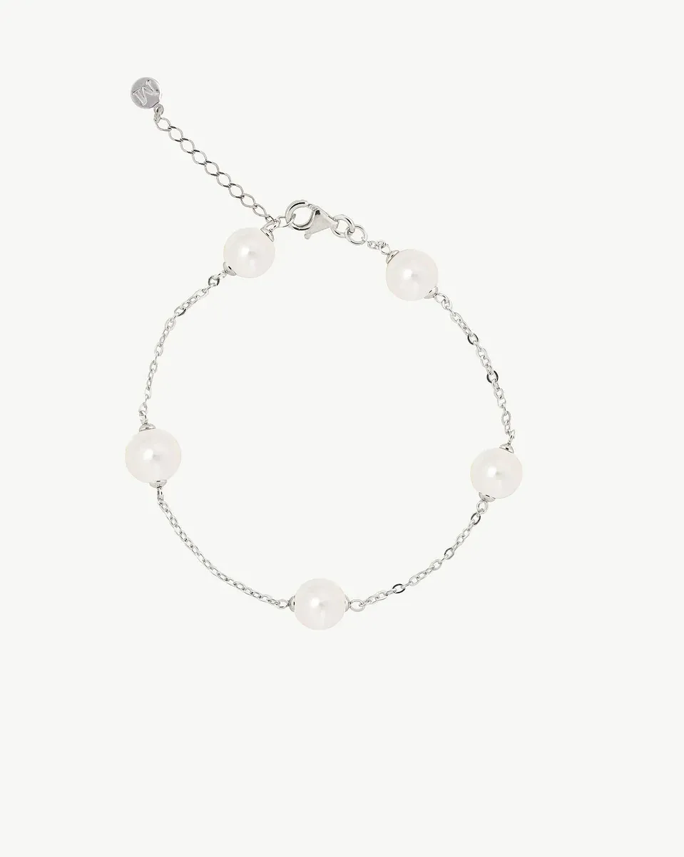 Vista superior de la pulsera con perlas blancas sobre fondo blanco, mostrando el cierre y la cadena ajustable.