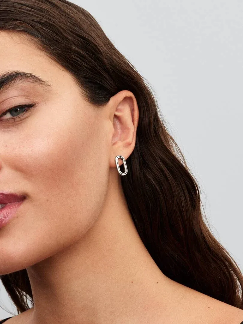 Close-up van een ovale zilveren oorring gedragen aan het oorlel, zijprofiel.