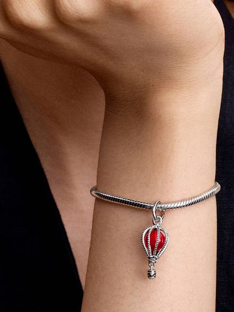 Charm ballon rouge sur un poignet, vue de profil avec fond sombre flou.