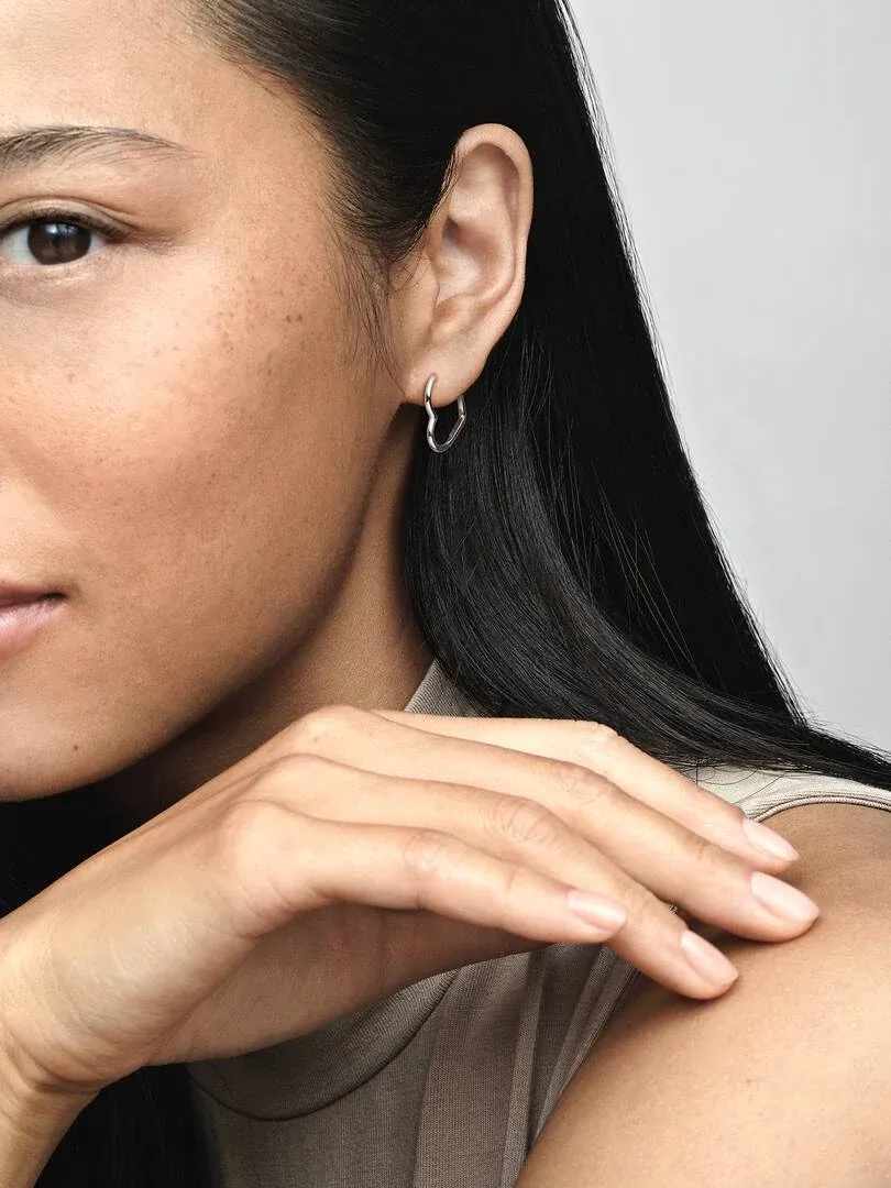 Close-up van een hartvormige oorring gedragen in het oor, zijaanzicht op model.