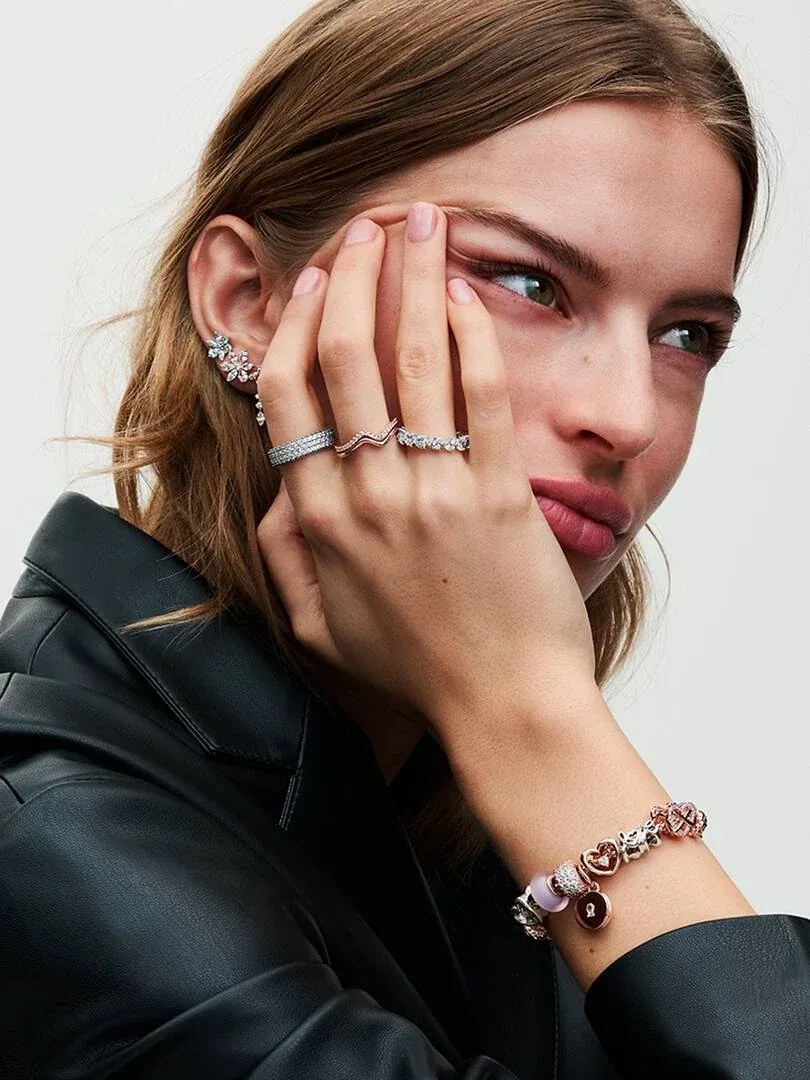 Gros plan d'un modèle portant un bracelet et des bagues, vue de profil sur fond blanc.