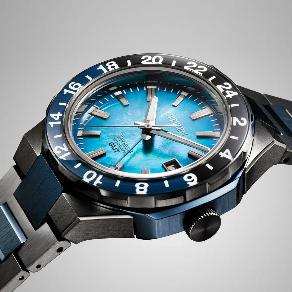 Primer plano en ángulo del dial azul texturizado y el bisel numerado sobre fondo gris neutro
