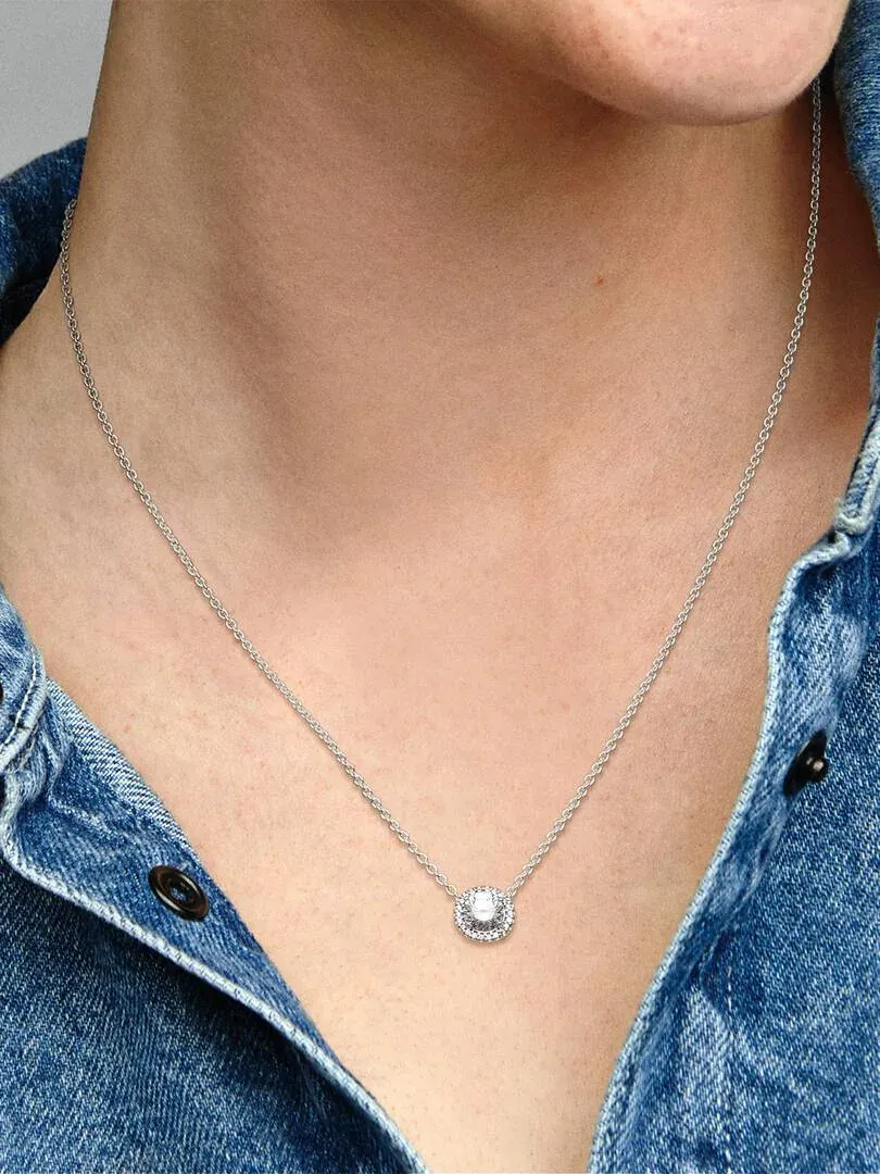 Close-up of the necklace with a circular cubic zirconia pendant on neck and denim shirt.