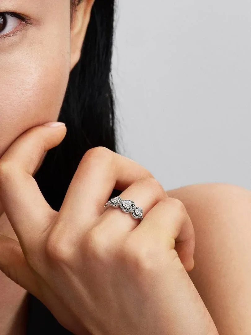 Primer plano del anillo de plata con gemas en forma de corazón puesto en el dedo, toma lateral sobre piel.