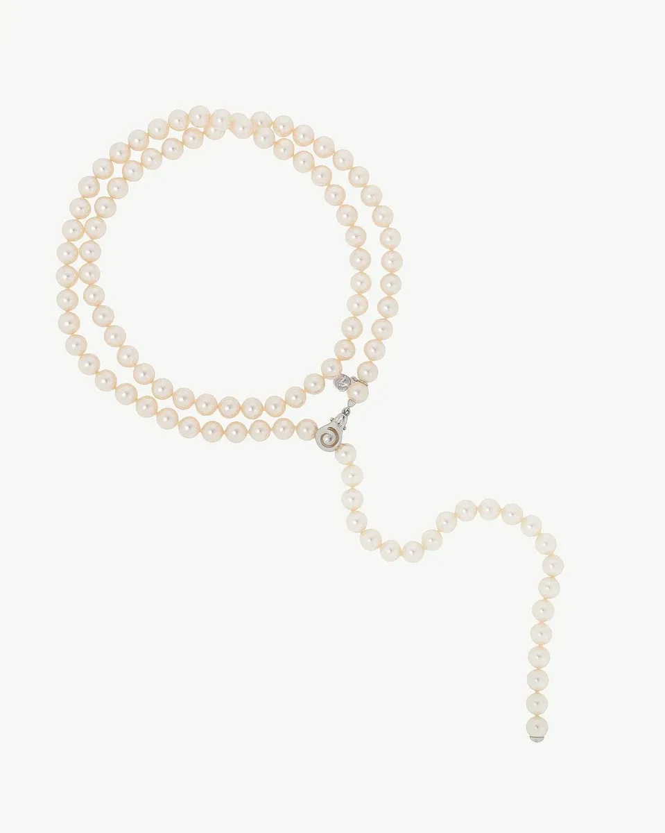 Collar de perlas blancas dispuesto en forma circular sobre fondo blanco, vista frontal completa.