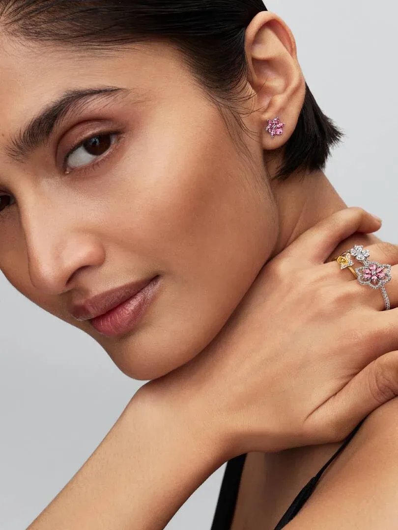 Nahaufnahme eines Models mit dem Bienenring und rosa Ohrsteckern, Seitenansicht vor neutralem Hintergrund.