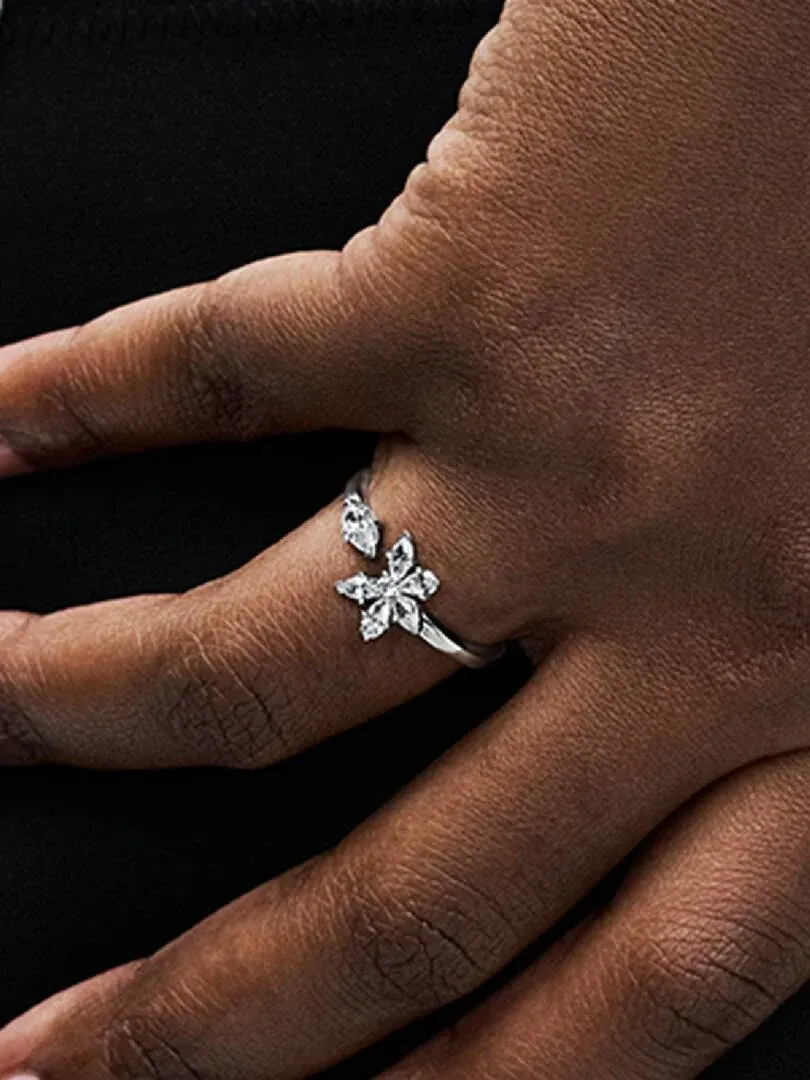 Nahaufnahme des silbernen Rings mit Zirkonia am Finger, Seitenansicht vor dunklem Hintergrund.