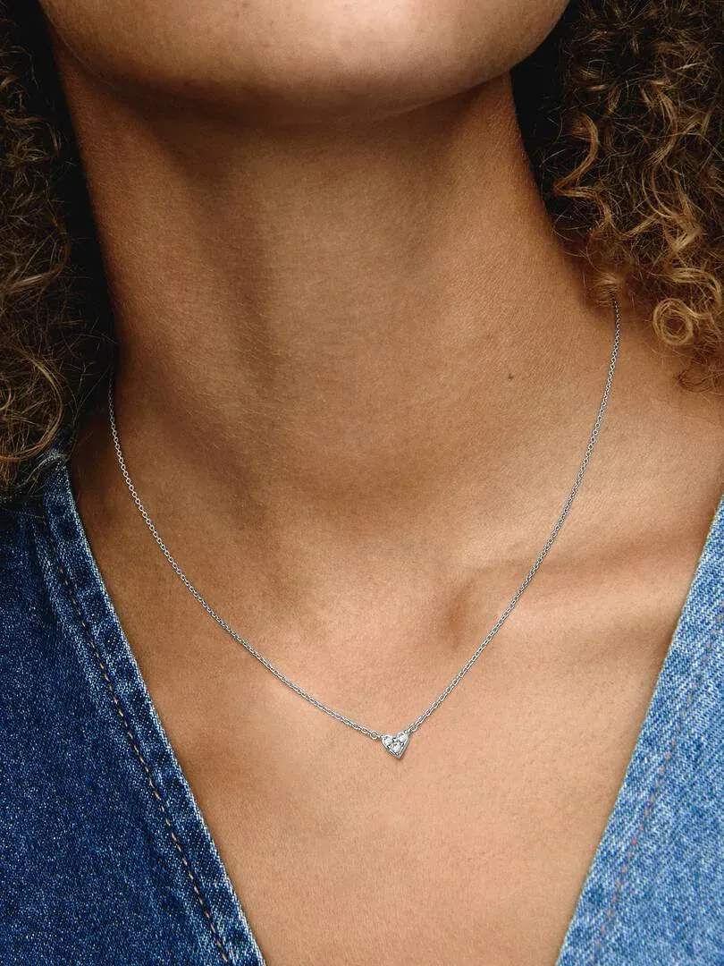 Close-up van de ketting met hart hanger gedragen om de nek van een model, wazige achtergrond.