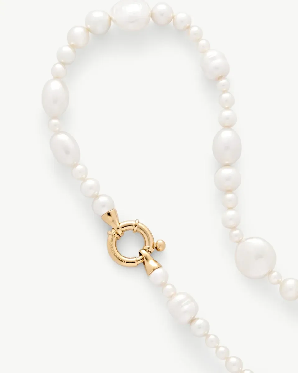 Close-up van het gouden marine sluiting op een witte parelketting, witte achtergrond.