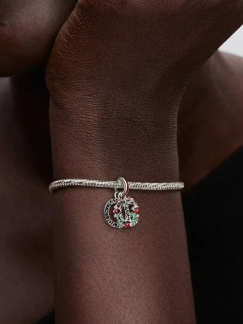 Gros plan d'un charm de Noël sur un bracelet porté au poignet, vue latérale avec fond flou.