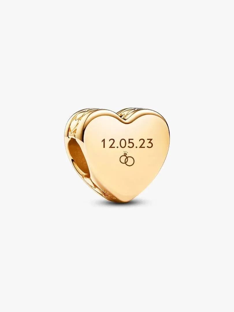 Close-up of heart charm with date and ring engraving, angled view on a white background.