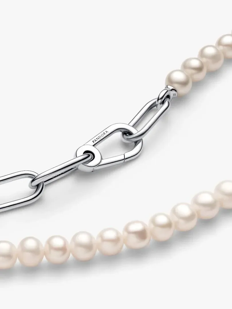 Diagonal close-up of silver links and white pearls on a white background.