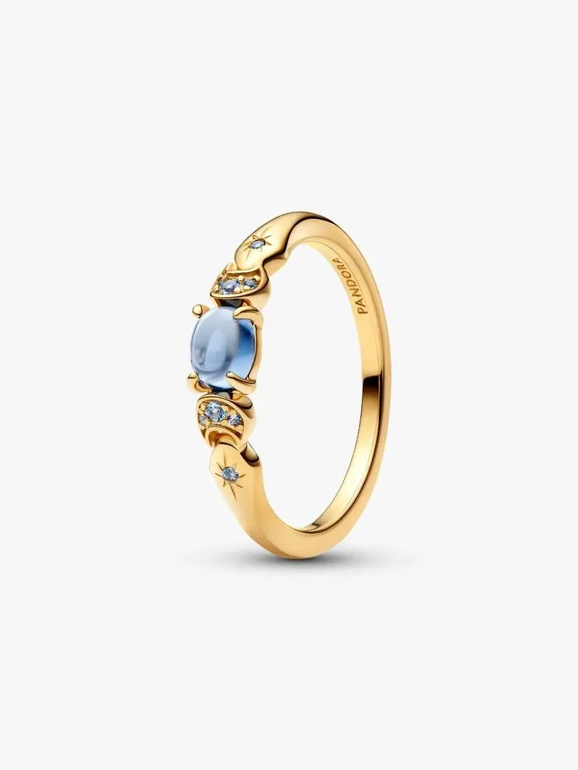Gold ring with central blue stone and crescent moon details, shown at a side angle on a white background.