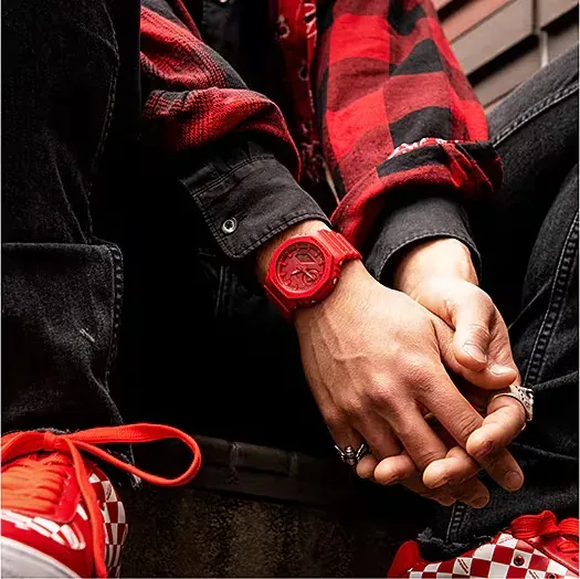 Plano medio del reloj rojo en la muñeca de un modelo con ropa urbana en tonos rojos y negros.
