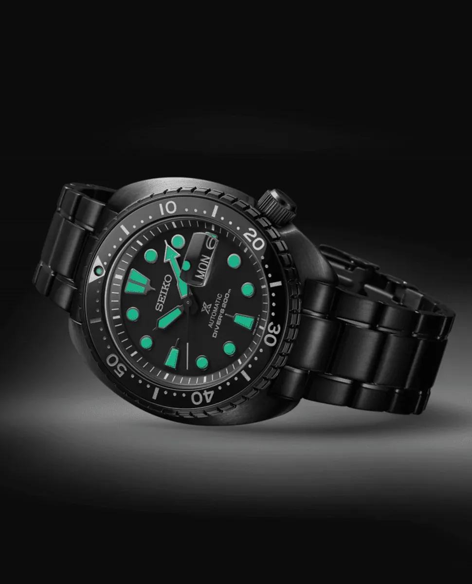 Reloj negro visto en perspectiva tres cuartos sobre fondo oscuro con iluminación focalizada.