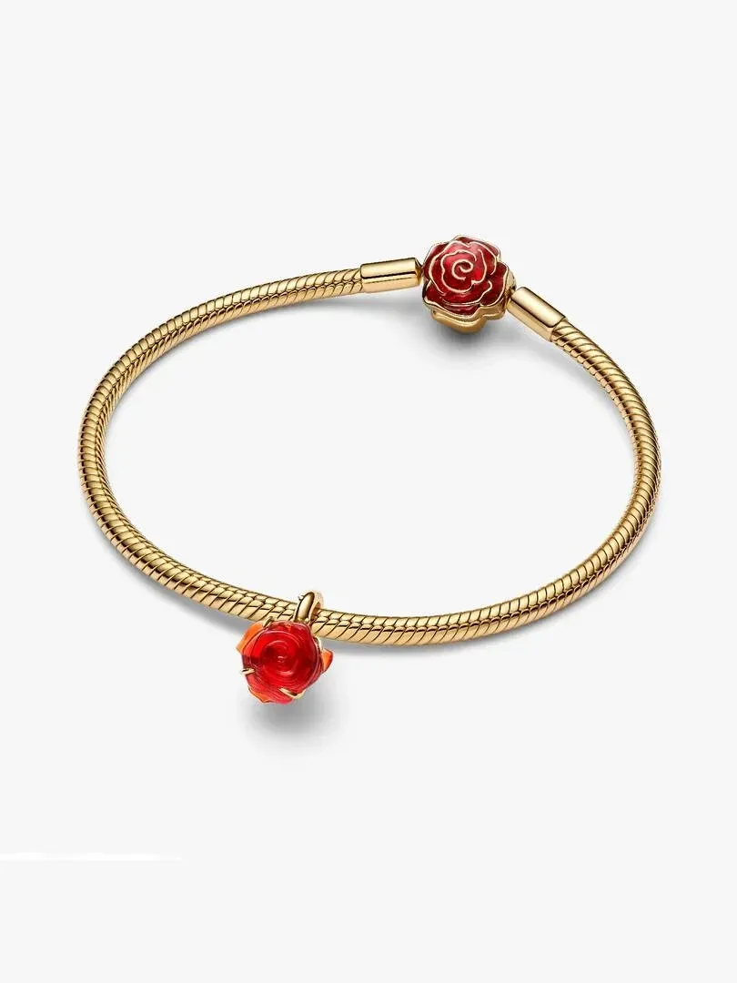 Bovenaanzicht van de gouden armband met twee rode rozen charms op een witte achtergrond.