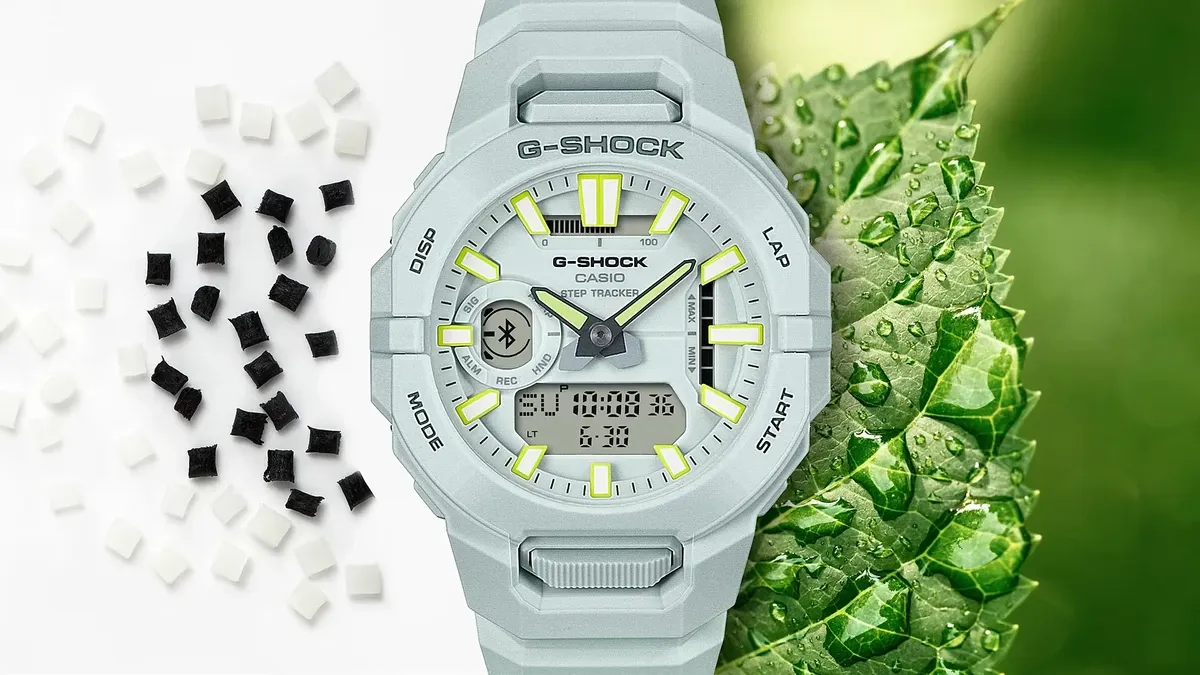 Reloj blanco centrado en composición dividida: pellets de resina sobre fondo blanco y hoja verde con gotas de agua.