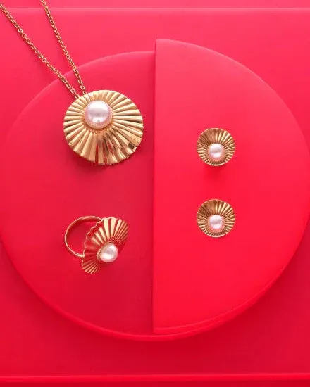 Set aus Halskette, Ring und Ohrringen auf rotem kreisförmigem Sockel, Draufsicht.